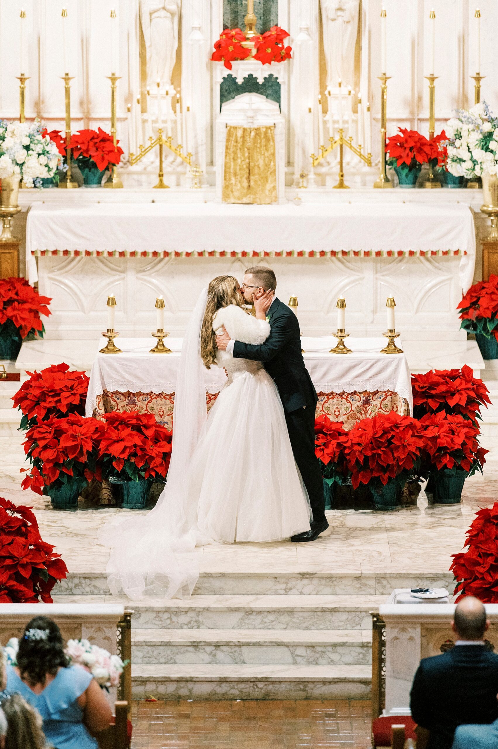 newlyweds kiss in front of alter inside Our Lady of Grace