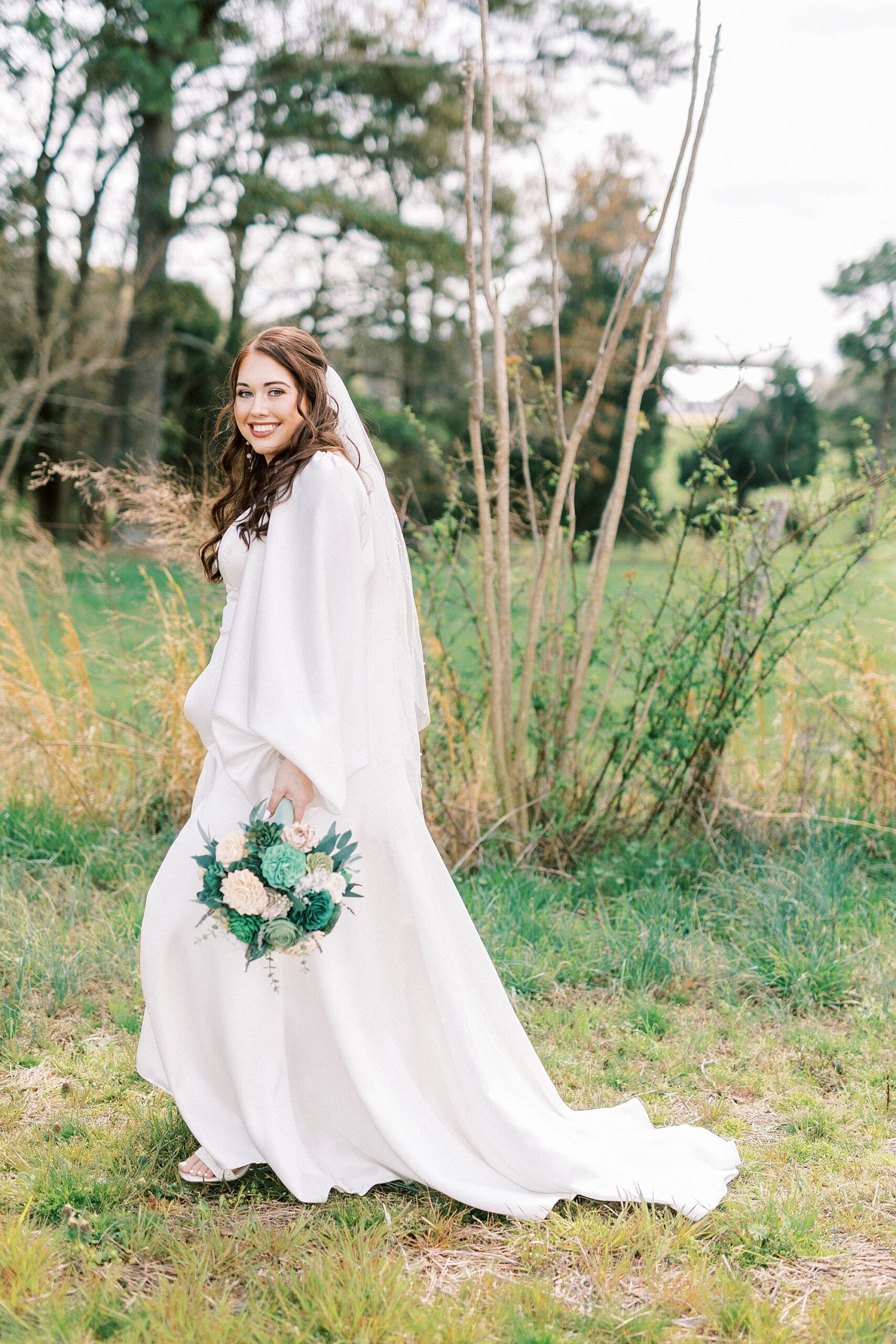 bride walks holding bouquet by her hip in pasture at Sixty Acres Farm
