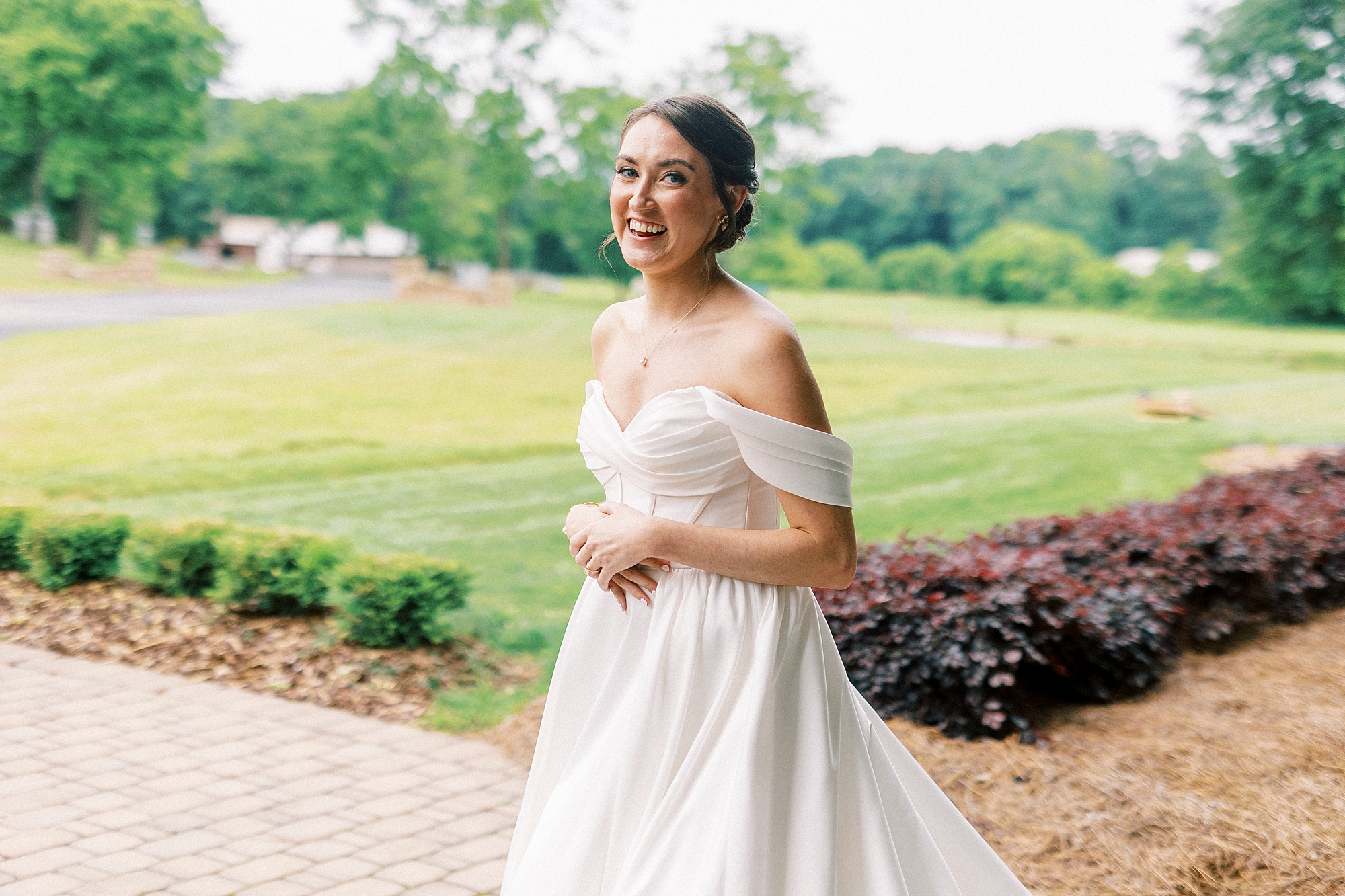 bride grins in off-the-shoulder wedding gown at Low Meadows Estate