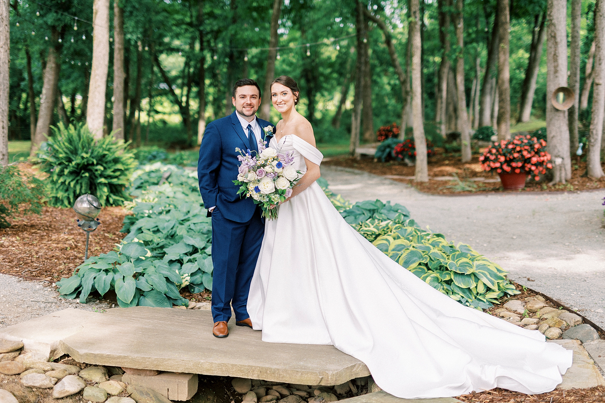 bride and groom stand on wooden bridge in gardens of Low Meadows Estate