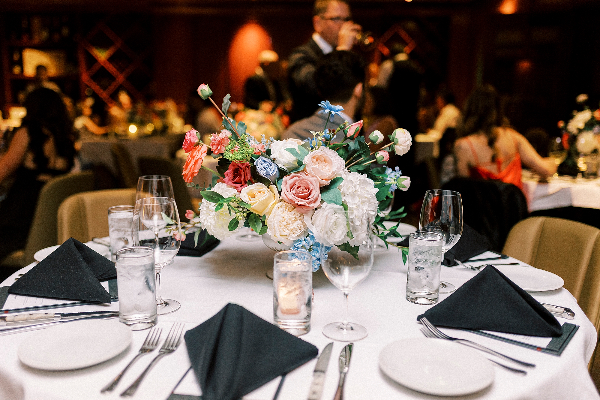 wedding reception tables with bright flowers inside Fleming's Steakhouse