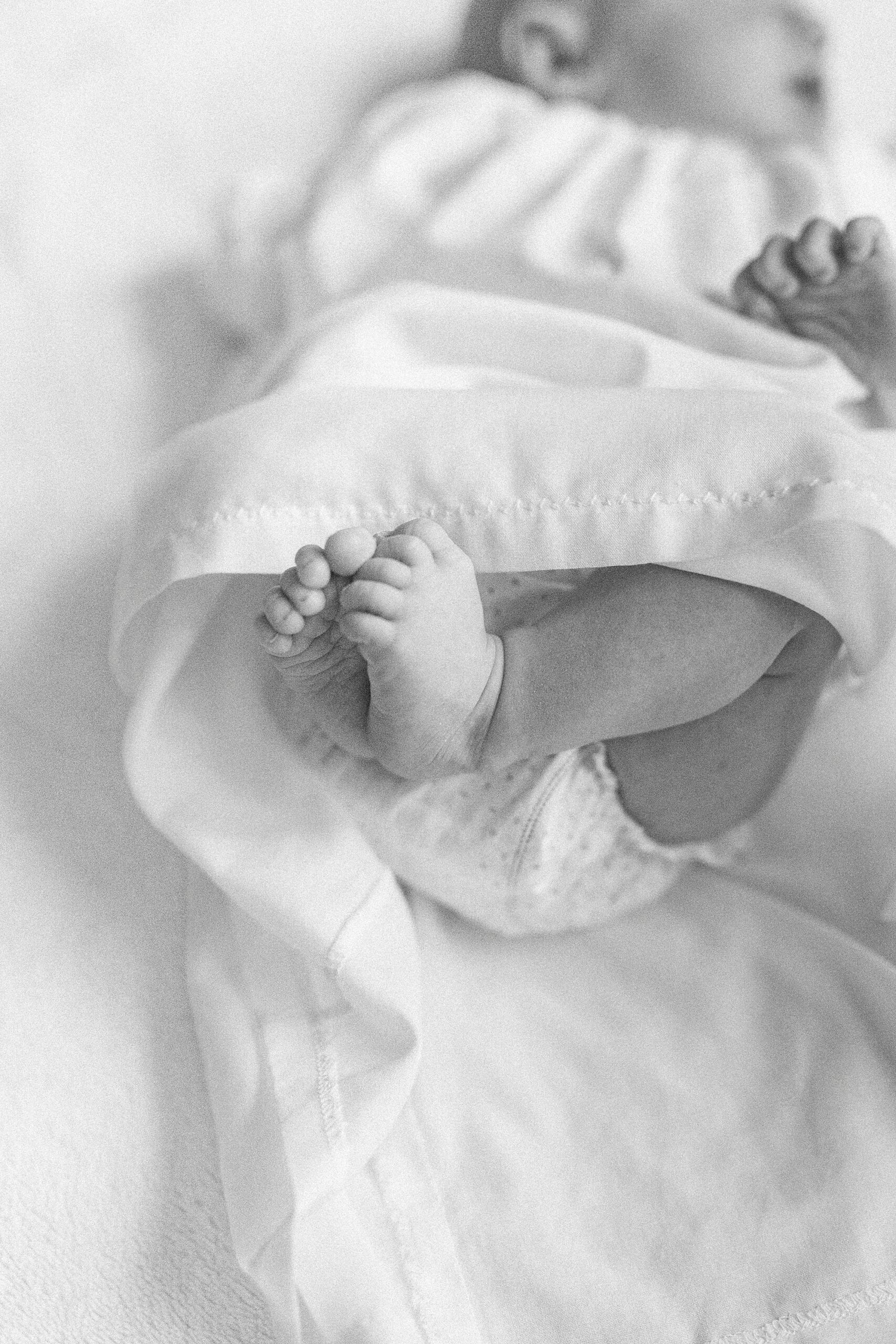 black and white photo of baby's feet sticking out of white dress