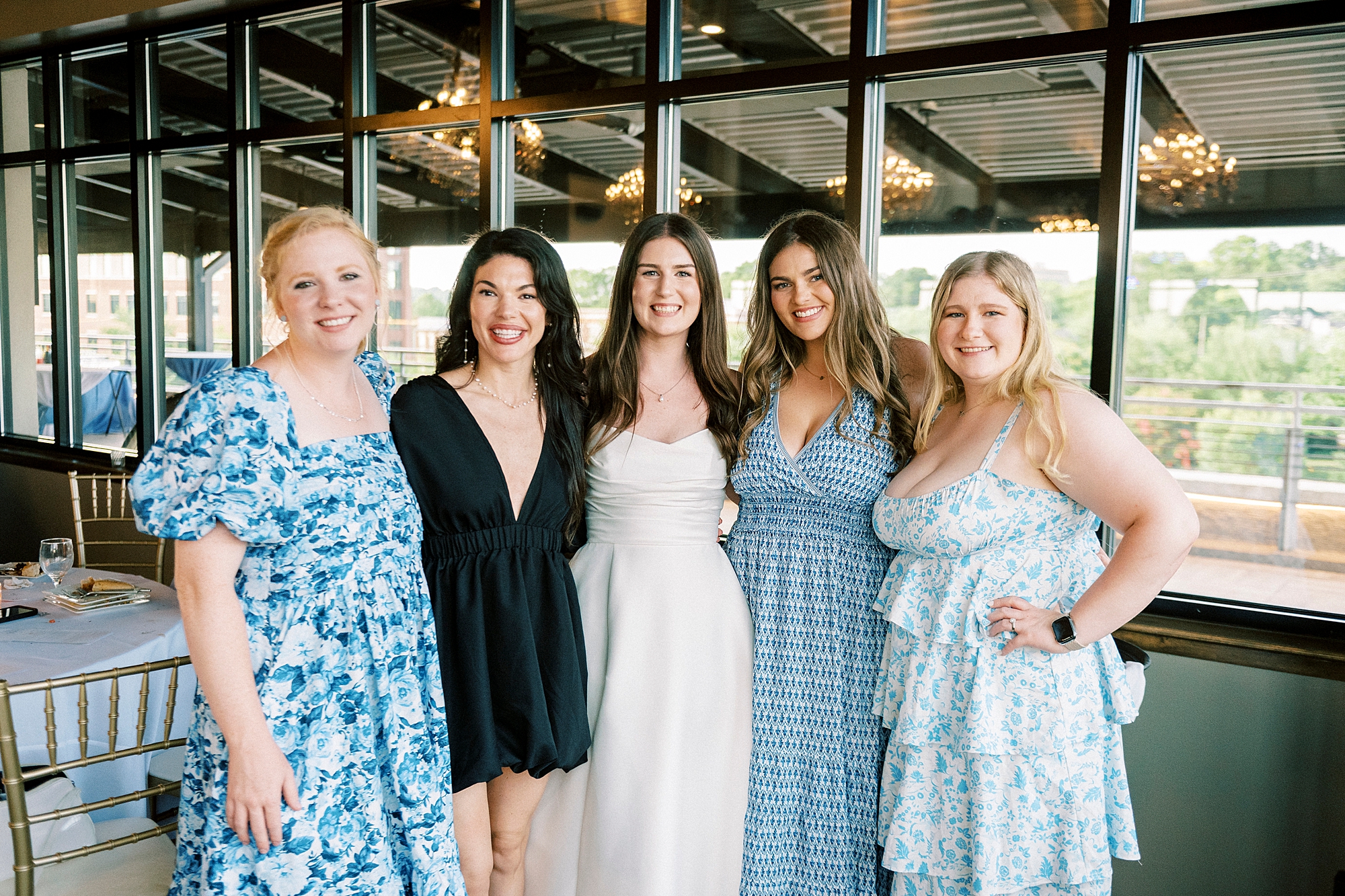 wedding guests in light blue dresses hug bride during reception at Terrace at Cedar Hill