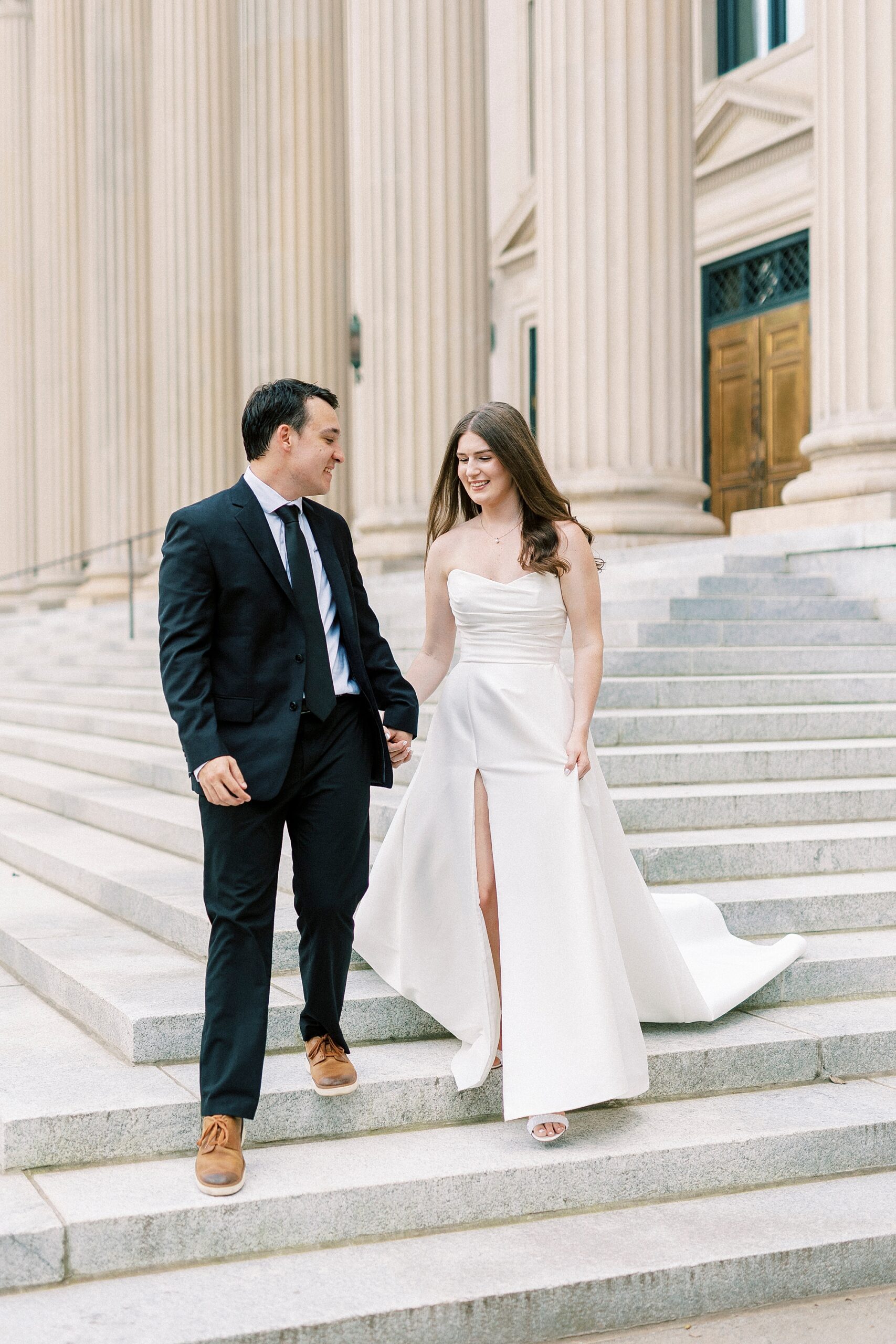 bride and groom hold hands walking down steps of building in Uptown Charlotte 